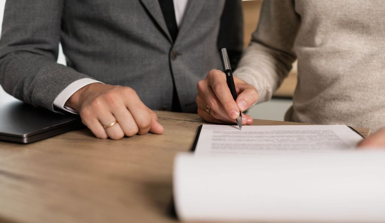 Businessmen signing documents at a wooden table in an office