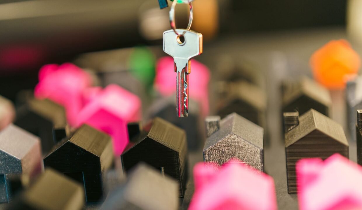 Miniature houses and a hand holding a house key, representing property price growth