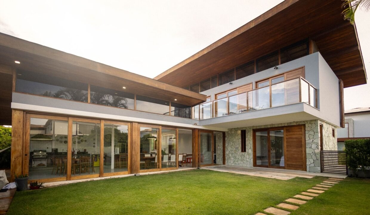 Modern luxury house with large glass windows, wooden finish and green lawn