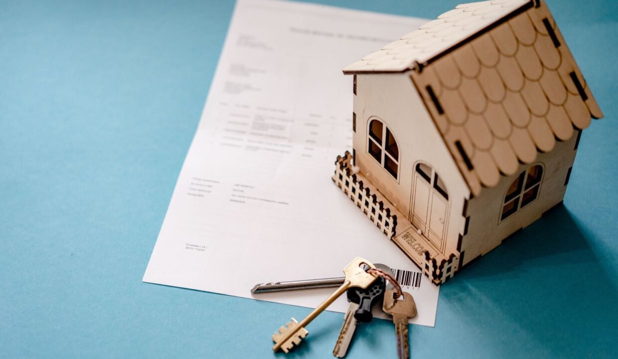 Wooden house model, keys and contract on a table
