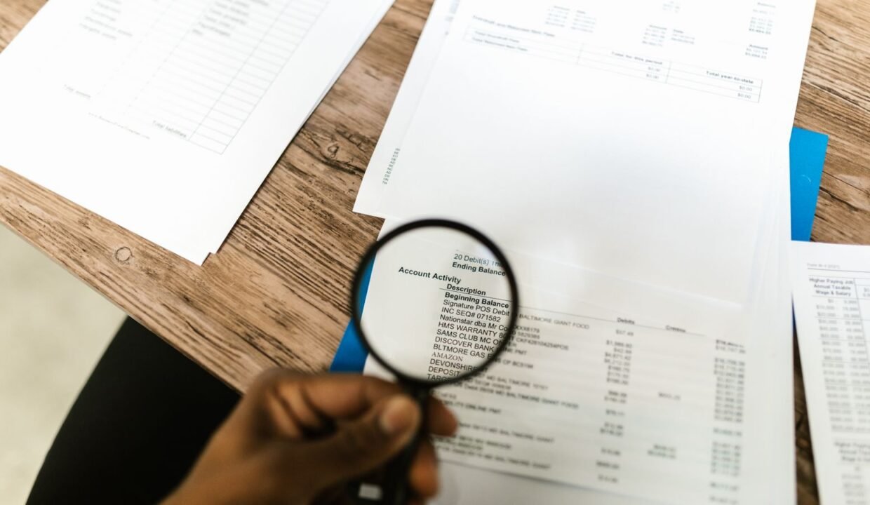 Hand holding a magnifying glass over documents